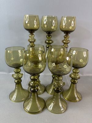 six verres à pied en verre vert, portant des numéros, posés sur une table