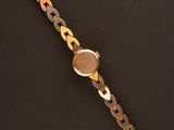 a close up of a gold watch on a black surface