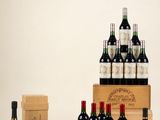 plusieurs bouteilles de vin et des cartons de vin posés sur une surface blanche