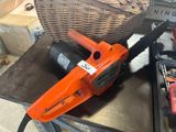 an orange chainsaw sitting on top of a table next to a basket of tools