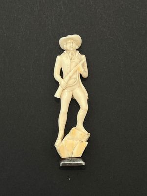 une figurine en ivoire sculpté représentant un homme portant un chapeau et une canne