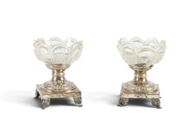 une paire de vases argentés posés sur des socles, disposés sur une surface blanche