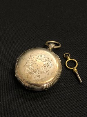 an antique silver pocket watch with a key on a black background