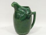 a green ceramic pitcher with a frog on it