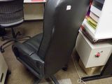 une chaise de bureau noire assise devant un bureau d'ordinateur