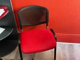a red chair next to a black desk with a computer on it