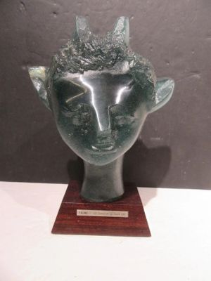 sculpture of a head with horns on a wooden base