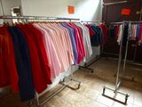 a lot of shirts hanging on a rack in a room