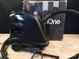 une image représentant un aspirateur posé sur une table, à côté d'une boîte