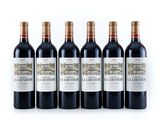 quatre bouteilles de vin rouge sont alignées sur une surface blanche