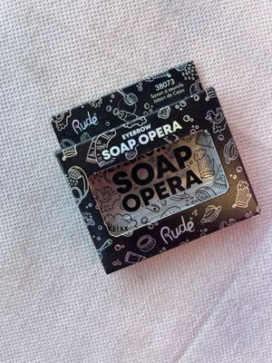 un savon de série télévisée dans une boîte noire et blanche, posé sur une serviette blanche