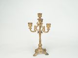 a gold candle holder with three candles on it