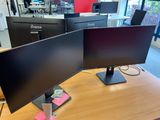 two monitors sitting on a desk in an office