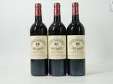 three bottles of red wine sitting on top of a white table