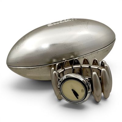 a silver watch sitting on top of a football shaped object