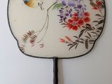 a fan with a painting of a bird and flowers on it
