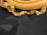 a gold oval mirror on the wall with a black background