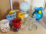 many different colored cups and vases sitting on a table