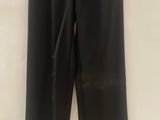 a black leather pants hanging on a hanger on a wall