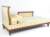 une chaise longue rayée jaune et blanche, avec des coussins