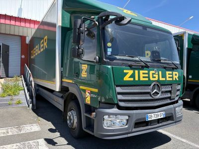 un camion vert garé sur un parking à côté d'un immeuble