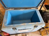 a blue cooler sitting on the floor next to other items