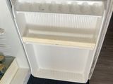 a white refrigerator with its door open on the floor