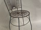 une chaise en métal posée sur une surface blanche