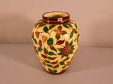 a yellow vase with red and green flowers on it
