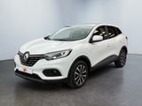 Une voiture blanche est garée dans une pièce au sol noir.