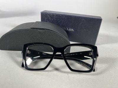 glasses are sitting on a white surface next to a black case