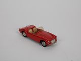 une petite voiture rouge posée sur une surface blanche