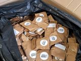 une boîte remplie de sacs en papier kraft sur lesquels sont collés des autocollants