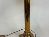 a gold table lamp with a white shade on top of it