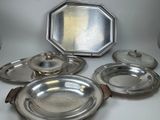cinq assiettes en argent et un miroir posés sur une table