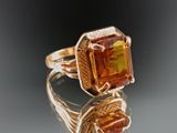 an image of a ring with an orange stone on top of a reflective surface
