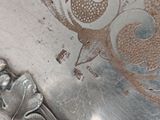 a close up of a silver plate with a bird design on it