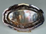 a silver platter with a metal handle on a stand