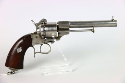 un vieux revolver avec une poignée en bois sur une surface blanche
