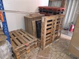 Des cartons et des palettes sont empilés dans une pièce où se trouve une échelle