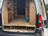 the back of a van with the door open and a shelf in the back