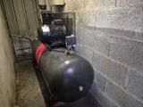 un réservoir muni d'une pompe, placé à côté d'un mur de briques