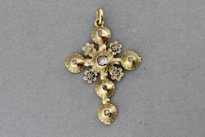 un gros plan d'une croix en or sertie de diamants sur une surface grise
