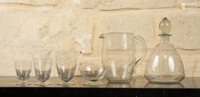 Des bouteilles et des verres sont alignés sur une étagère devant un mur de briques.