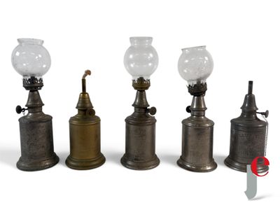 three old fashioned oil lamps are lined up on a white surface