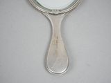 a small mirror with a silver handle on a table