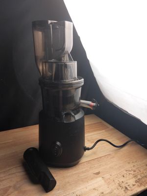 un mixeur noir posé sur une table en bois devant une fenêtre