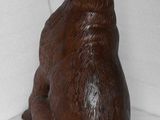 a wooden statue of a dog sitting on a white surface