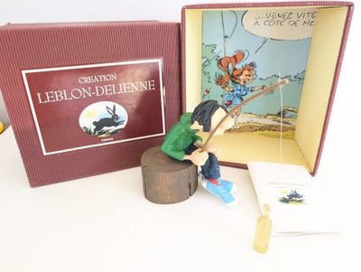 une figurine représentant une petite fille assise sur une souche d'arbre, avec un livre devant elle