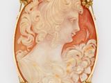 Une broche plaquée or représente le profil d'une femme.